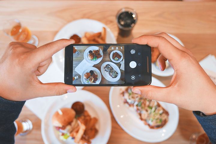 Hands holding a phone over a table of dishes